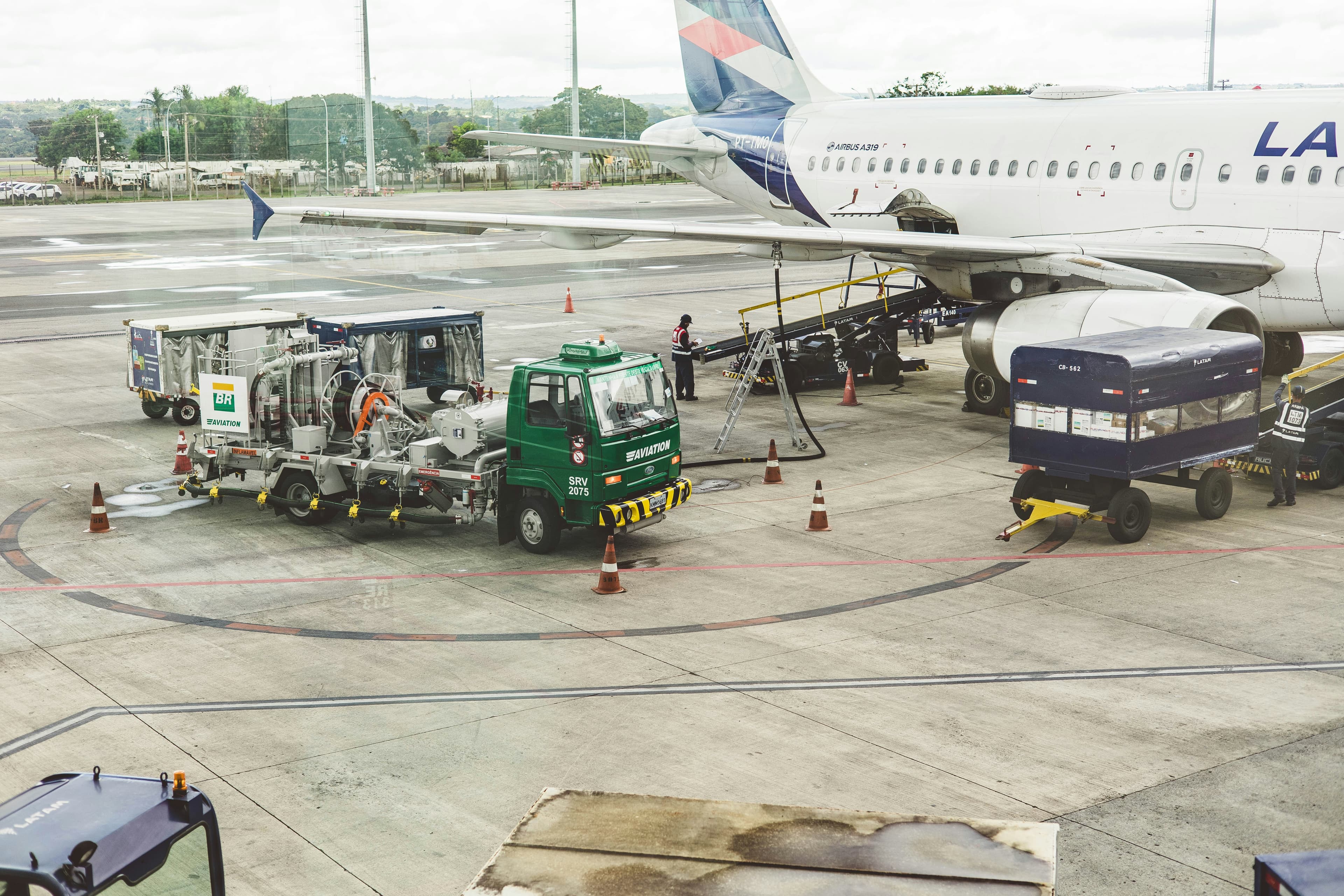 An aviation fuel truck connected to an aircraft on the tarmac